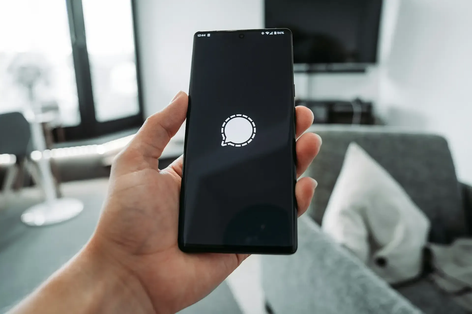 Man holding phone with private messaging app loading in living room