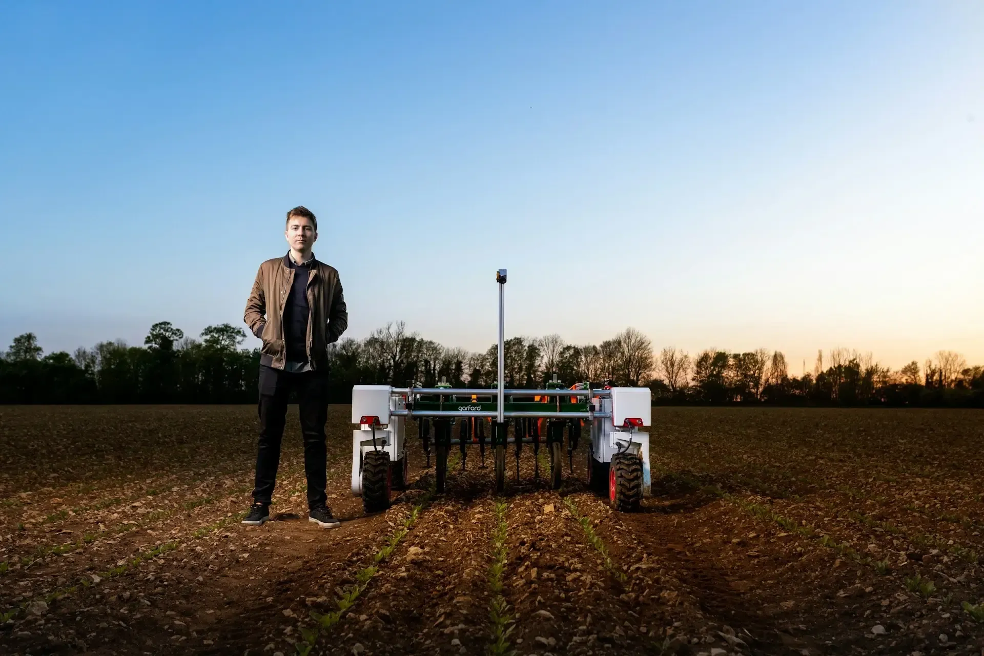 Man on a field with a real agricultural robot